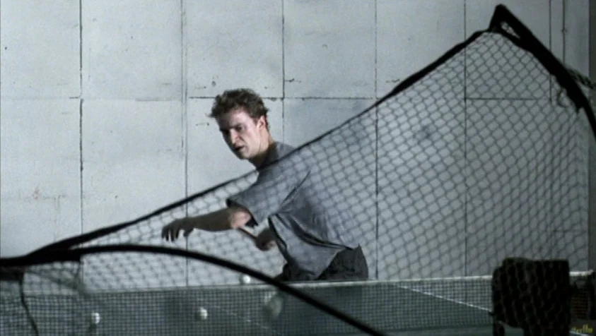 71 Fragments of a Chronology of Chance (1994) movie still: medium — A plain room with light grey walls featuring large, visible concrete panel…
