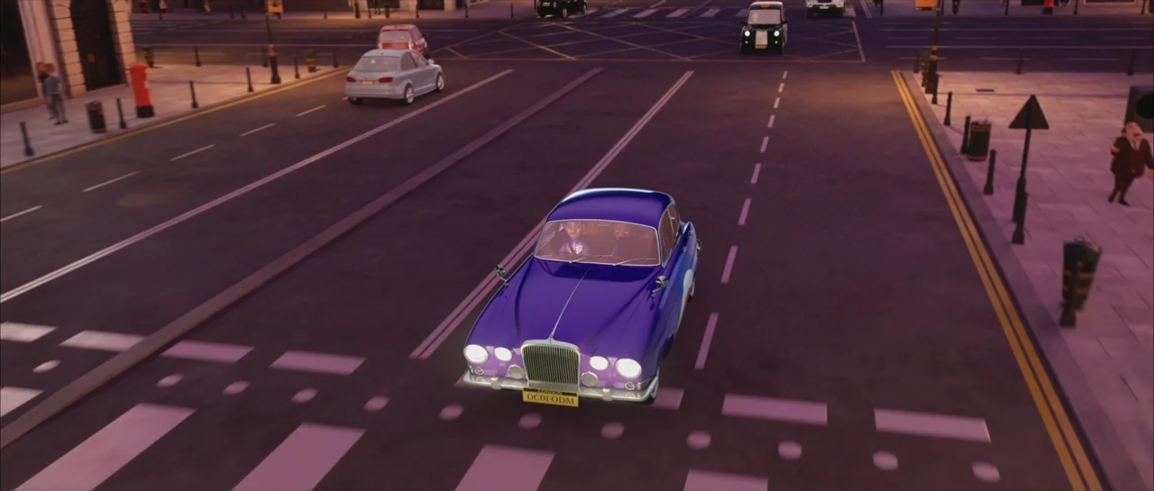 Mummies (2023) movie still: wide — An empty urban intersection at night with a purple sedan stopped at a crossing. The car is positioned in the…