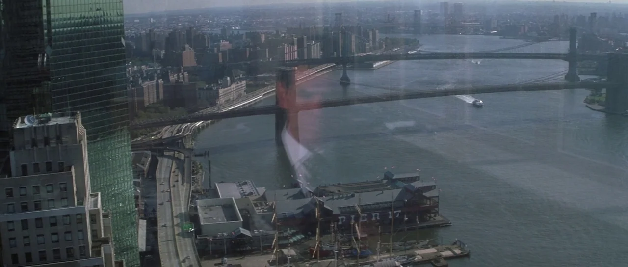 The Thomas Crown Affair (1999) movie still: establishing — A high-angle view looks down at the New York City waterfront near the East River. Bridges…