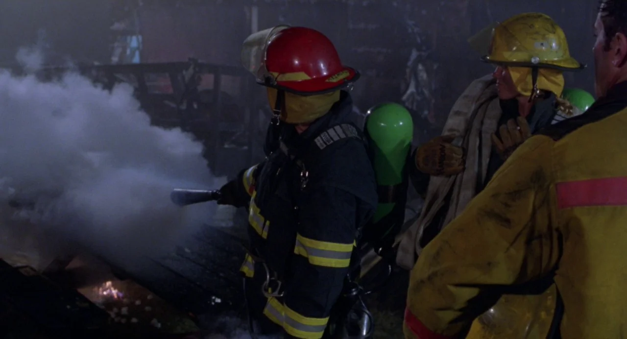 Drop Dead Gorgeous (1999) movie still: medium — Three firefighters work in a smoky area during a nighttime emergency operation. One firefighter…