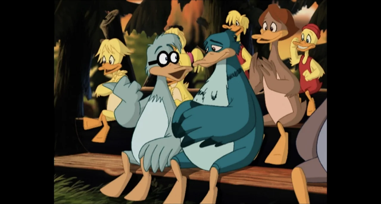 The Sissy Duckling (1999) movie still: medium — A group of stylized animated ducks sit together on a wooden bleacher bench outdoors. The characters…