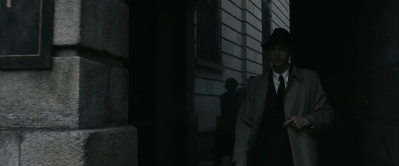 Freud's Last Session (2023) movie still: medium — A stone building exterior with heavy shadows obscures the depth of the passage. A man wearing a…