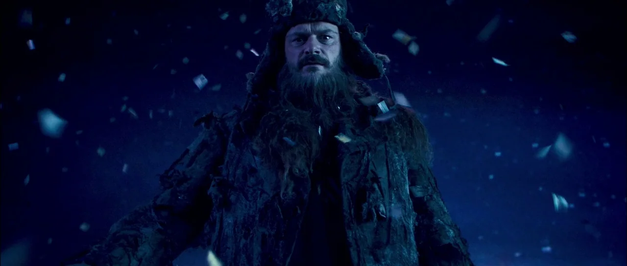 Bunny and the Bull (2009) movie still: medium — A dark, void-like exterior space with debris floating in the air around the subject. A bearded man…