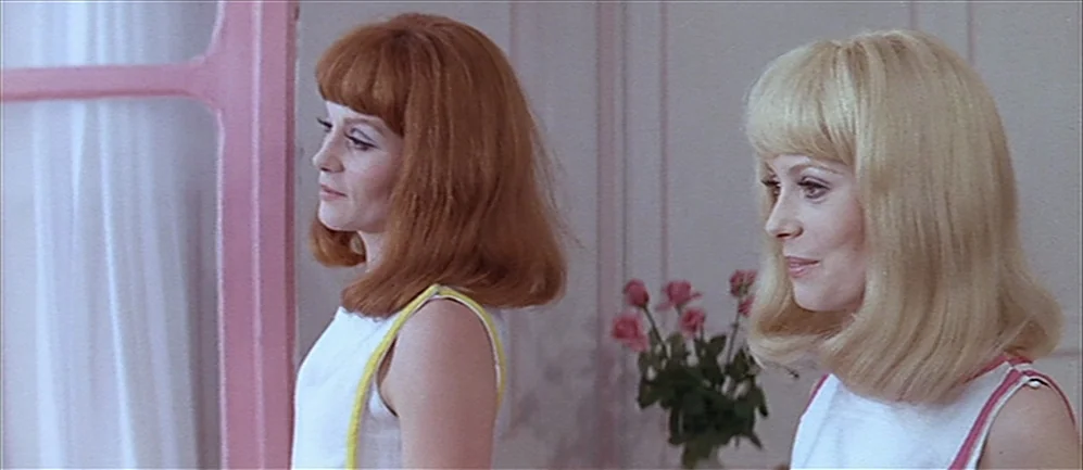 Les Demoiselles de Rochefort (1967) movie still: medium — A light-colored room features pink trim around a window and a floral arrangement. Two…