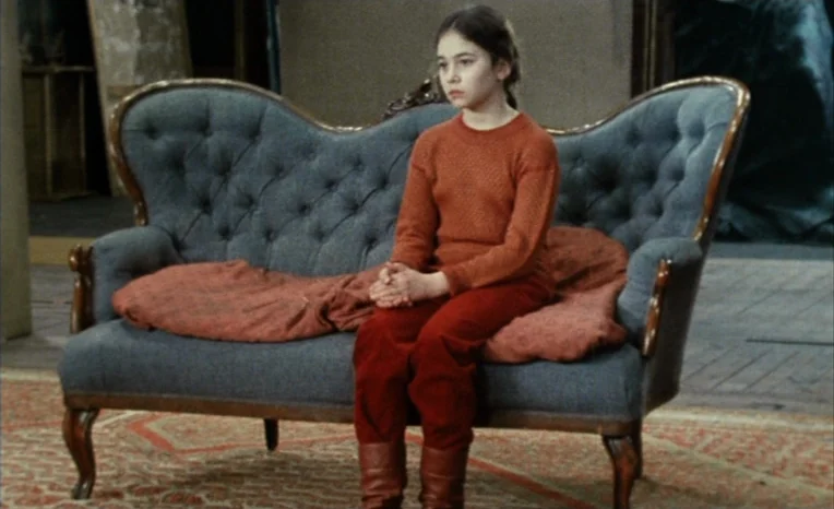 After The Rehearsal (1984) movie still: medium — A girl sits on a tufted Victorian-style settee in an sparsely furnished room. She keeps her hands…