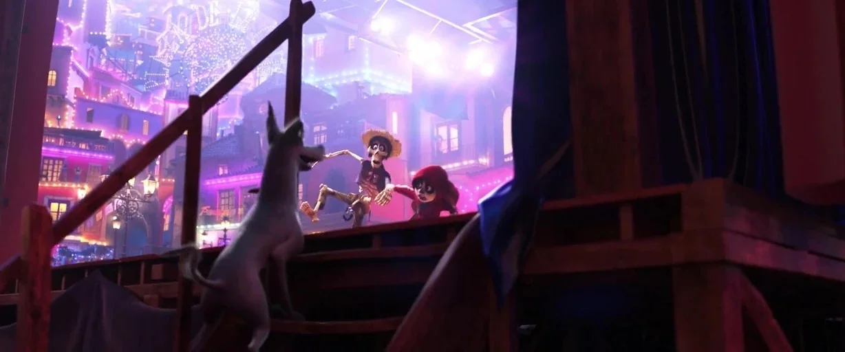 Coco (2017) movie still: wide — A wooden platform overlooks a densely packed, brightly lit Mexican-style town at night. A skeleton and a child in a…