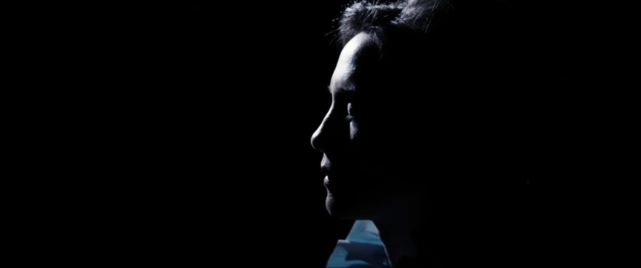 The Conjuring (2013) movie still: closeup — A person is positioned against a completely black background with no visible surroundings. The subject…