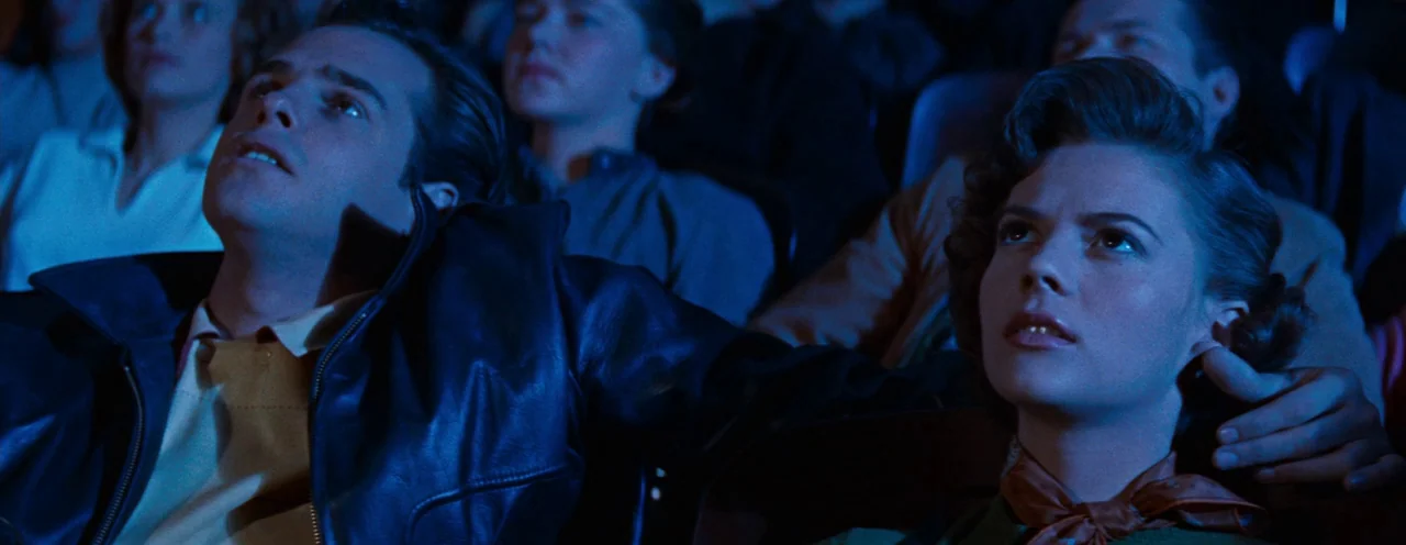 Rebel Without A Cause (1955) movie still: medium — A dimly lit movie theater audience sits in tiered rows watching a film. The foreground features a…
