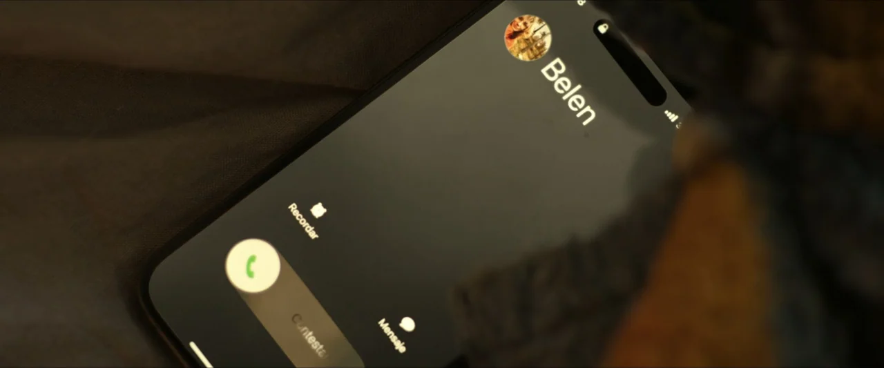 Apocalypse Z: The Beginning of the End (2024) movie still: closeup — A smartphone rests on a dark fabric surface displaying an incoming call screen.…