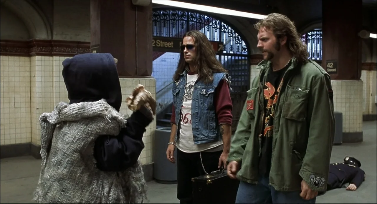 Little Nicky (2000) movie still: fullbody — A tiled subway platform features arched entrances and ornate metal gates in the background. Three…