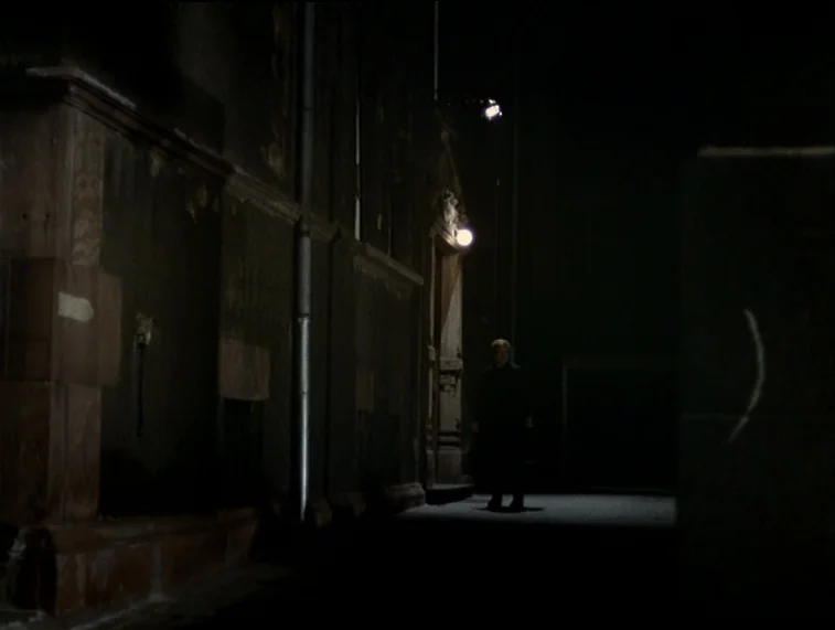 Mother Kusters Goes To Heaven (1975) movie still: wide — A narrow stone alleyway at night features dark, weathered walls and a single streetlamp. A…