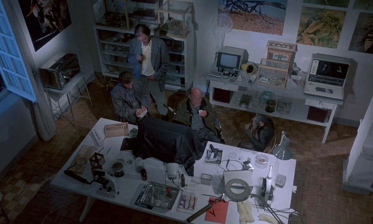 Phenomena (1985) movie still: wide — A research laboratory contains a large table covered in scientific equipment and biological specimens. Three…