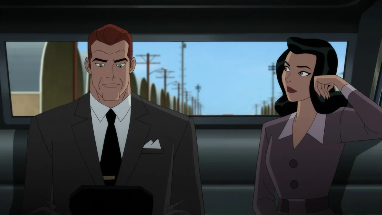 Superman: Red Son (2020) movie still: medium — Two individuals sit in the backseat of a vehicle driving through a rural area. A man and a woman in…