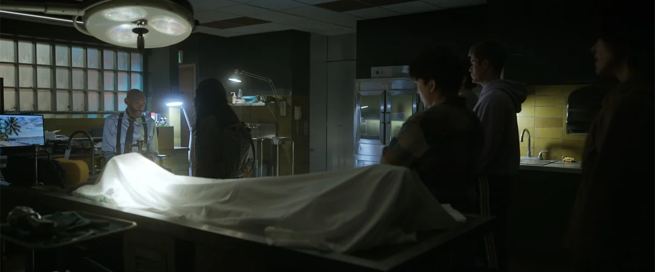 Final Destination Bloodlines (2025) movie still: medium — A sterile professional room with stainless steel equipment and a large metal refrigerator…