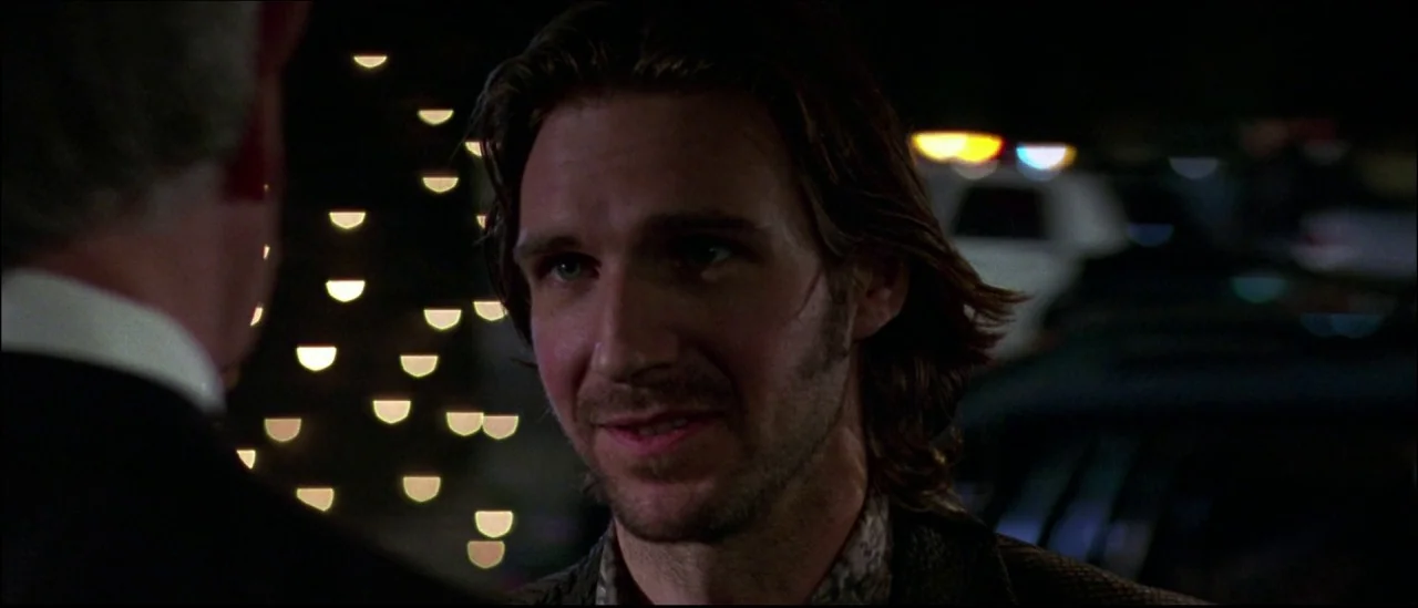 Strange Days (1995) movie still: closeup — A dark night setting with distant blurred lights in a large open outdoor area. A man with brown hair…