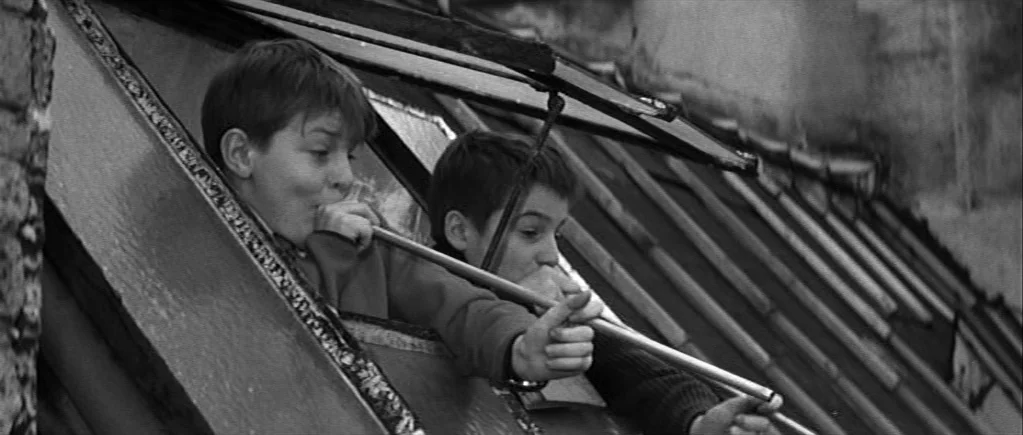 The 400 Blows (1959) movie still: medium — Two young boys lean from an open skylight window on a slanted slate roof. They point a long metal pipe…
