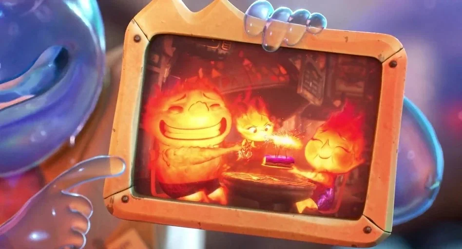 Elemental (2023) movie still: closeup — A framed photograph shows two orange flame parents and a child sitting together. The child blows on a…