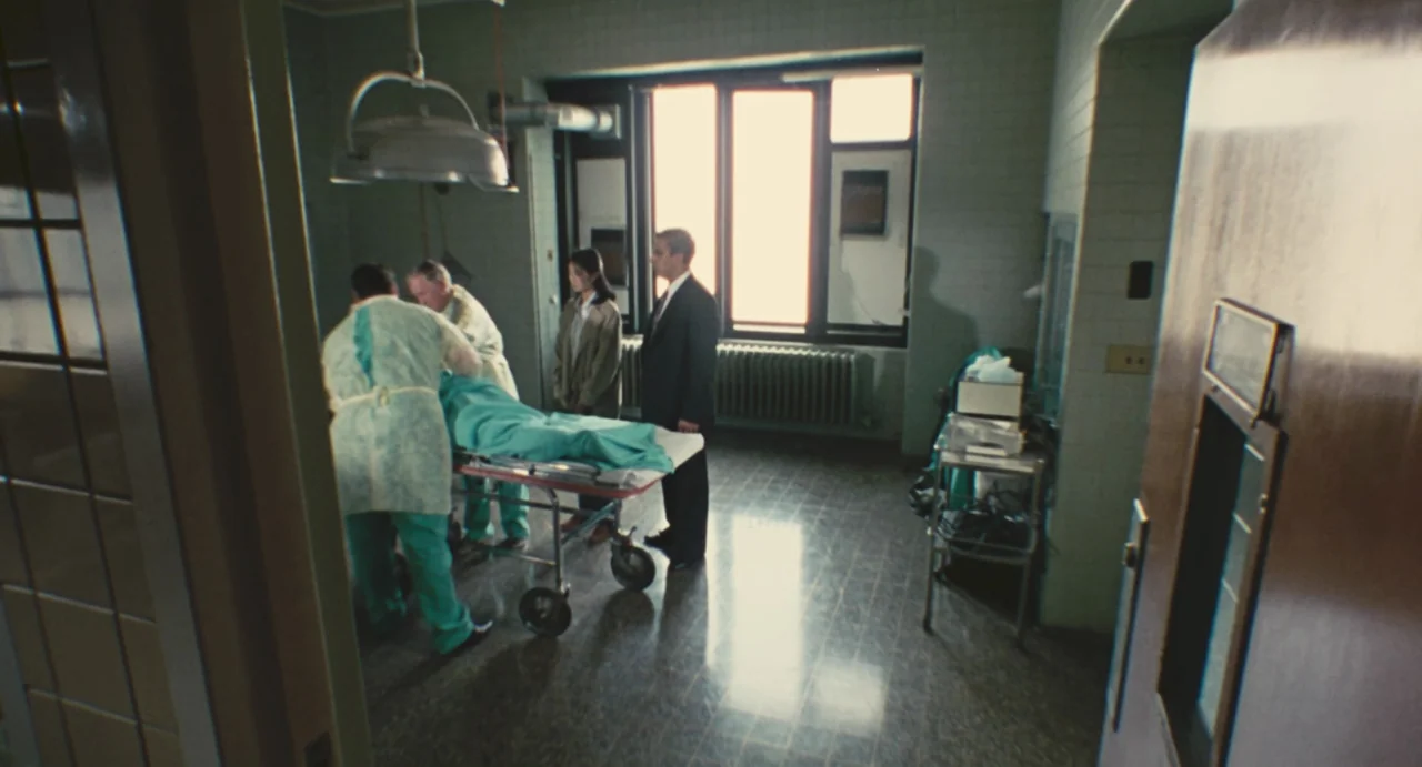 Comrades: Almost A Love Story (1996) movie still: wide — A sterile medical room features pale green tiled walls and a large windowed exterior wall.…