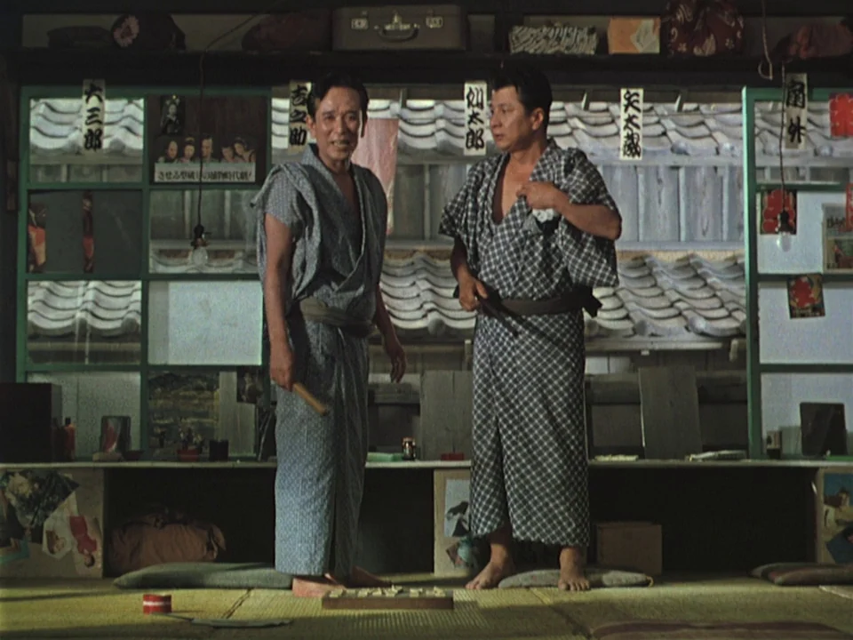 Floating Weeds (1959) movie still: fullbody — A traditional Japanese room features sliding windows looking out onto a tiled roof. Two men stand…