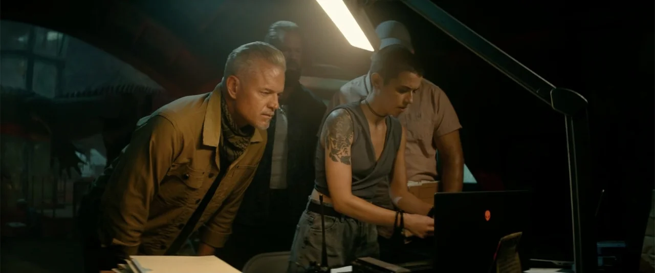 Bad Boys: Ride or Die (2024) movie still: medium — A dimly lit room contains a group of people standing around a glowing laptop. They look toward…
