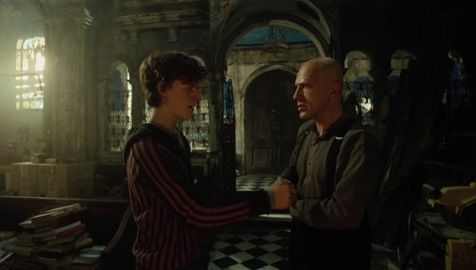 The Zero Theorem (2013) movie still: medium — An abandoned, cluttered church interior features a black and white checkered floor and archways. A…