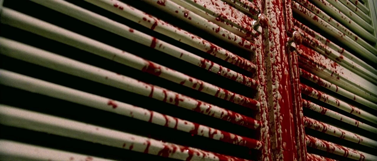 Haute Tension (2003) movie still: closeup — A pair of white louvered doors are covered in thick, viscous red liquid. The substance is dripping down…