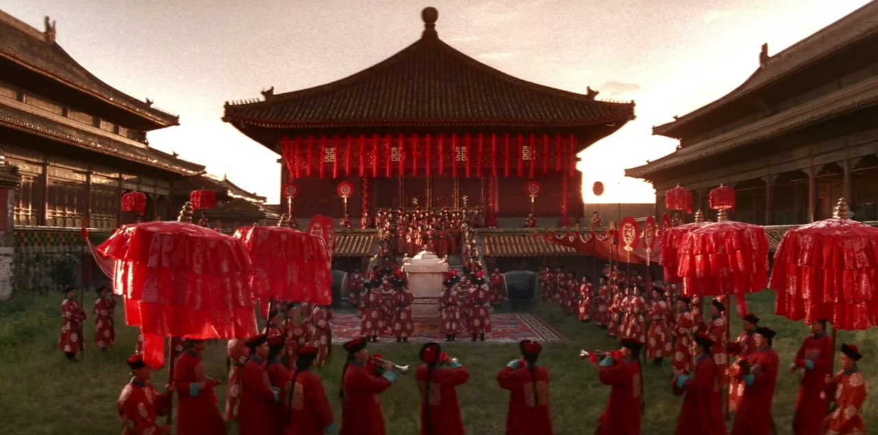 The Last Emperor (1987) movie still: wide — A vast courtyard sits before a traditional Chinese temple building adorned with red fabric banners. Many…