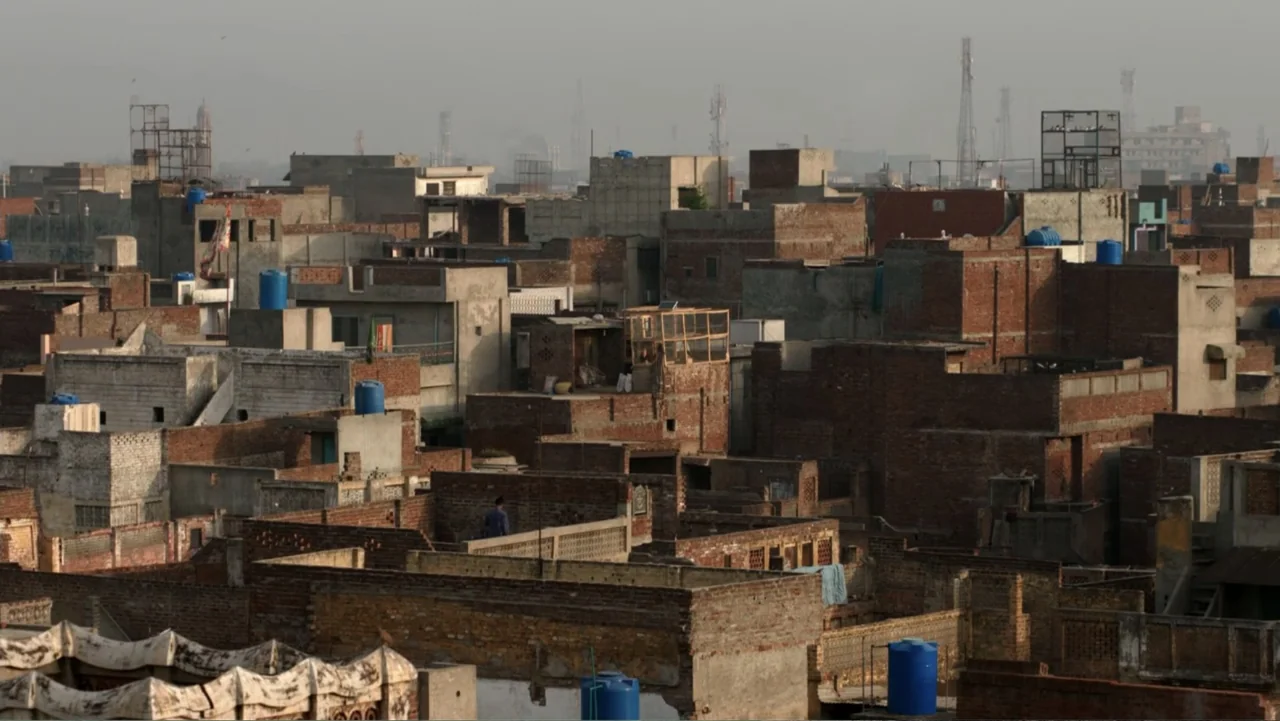 A Girl in the River: The Price of Forgiveness (2015) movie still: establishing — A dense urban landscape features flat brick roofs and scattered…