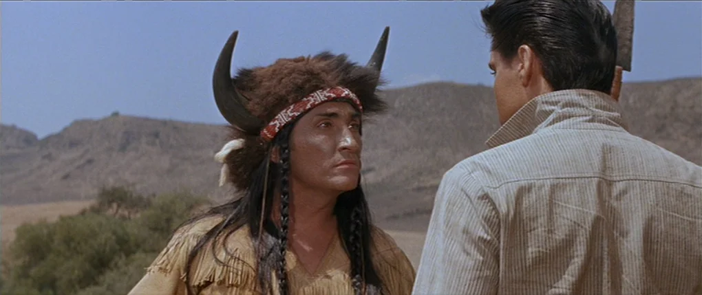 Flaming Star (1960) movie still: medium — An arid desert landscape serves as the backdrop for two men facing each other. The individual on the left…