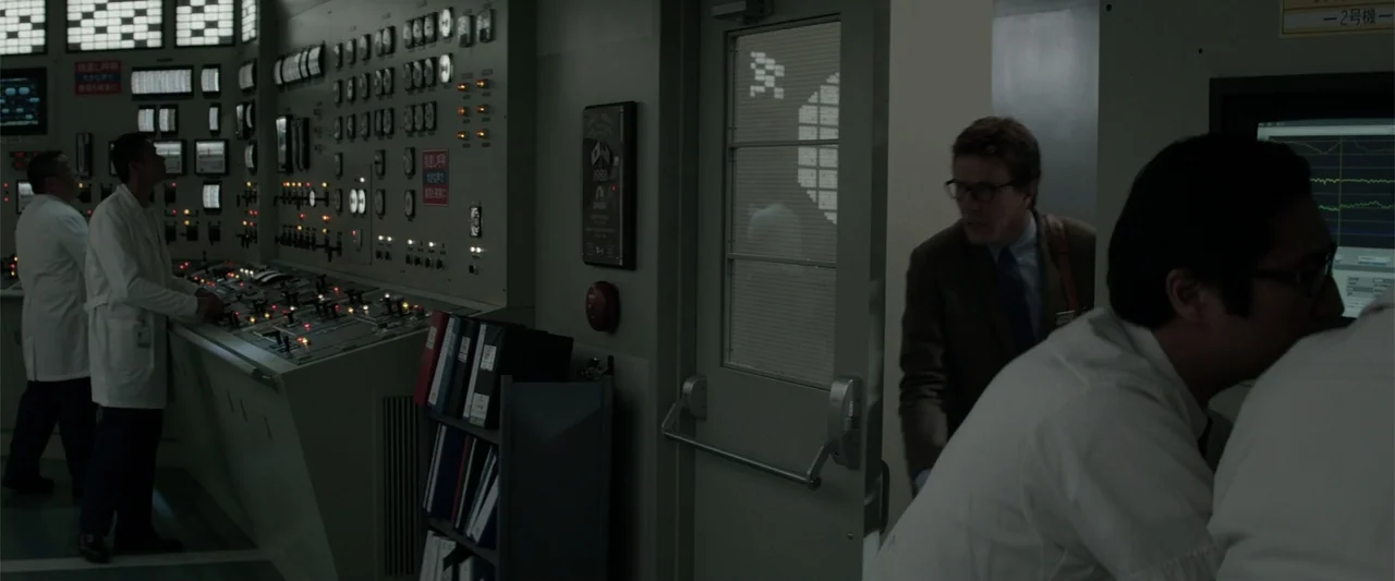 Godzilla (2014) movie still: medium — An industrial nuclear control room contains rows of analog gauges and computer monitoring stations. A man in a…