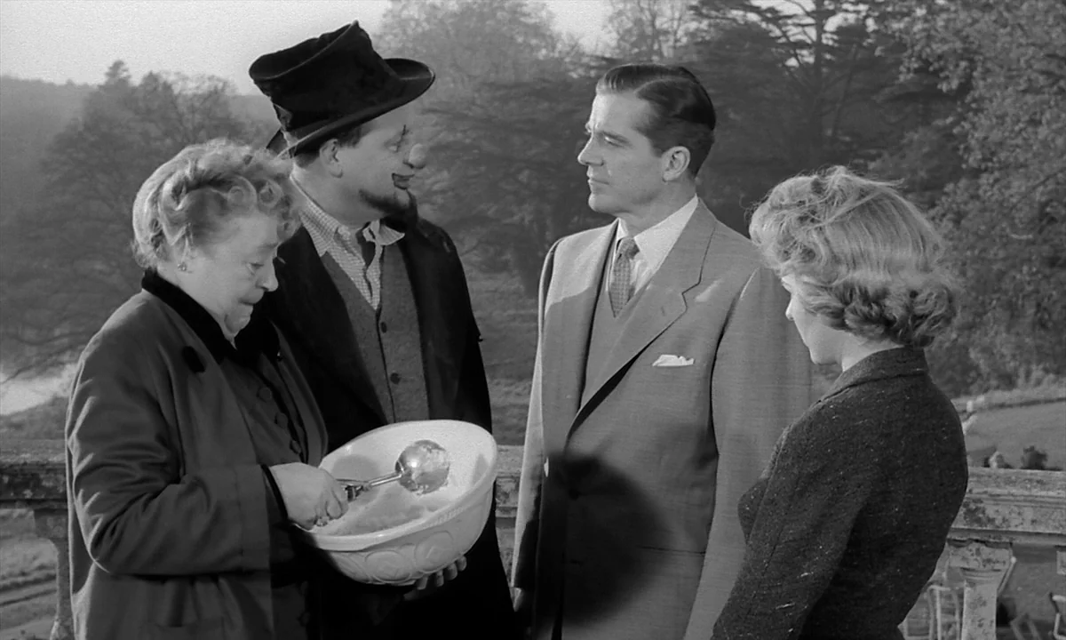 Night Of The Demon (1957) movie still: medium — A stone balcony overlooks a distant line of bare trees on a cloudy day. Four individuals gather near…