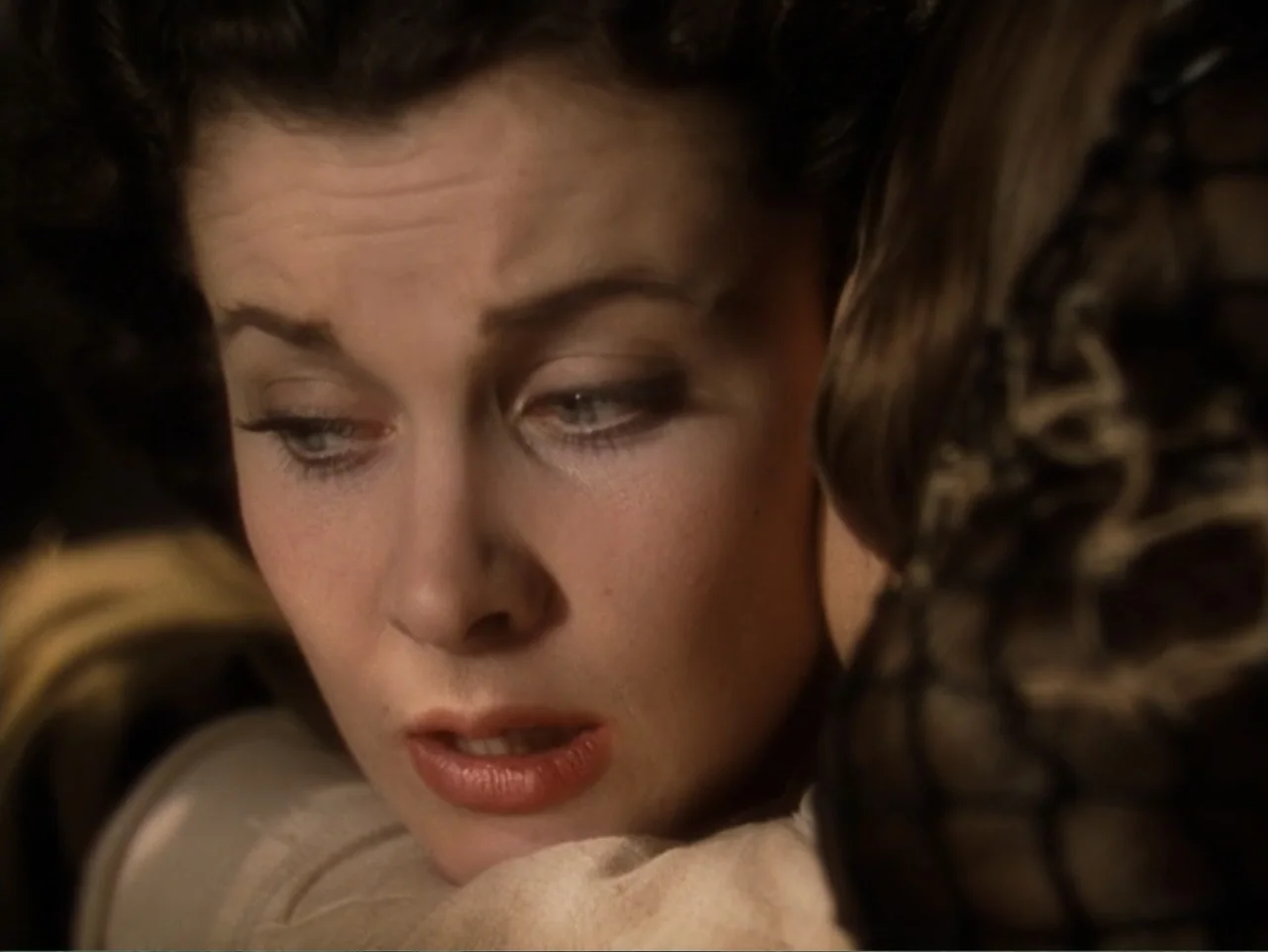 Gone with the Wind (1939) movie still: closeup — An interior space with a person partially in frame in the foreground. A woman rests her head…