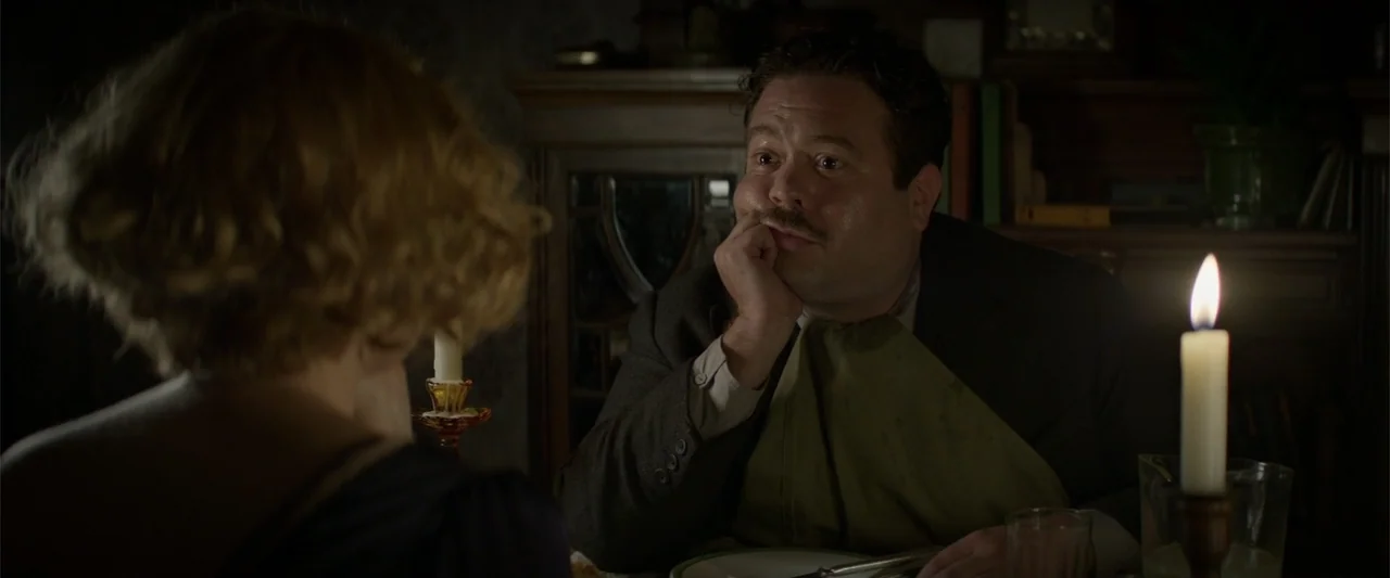 Fantastic Beasts and Where to Find Them (2016) movie still: medium — A dimly lit 1930s dining room features dark wood furniture and flickering…