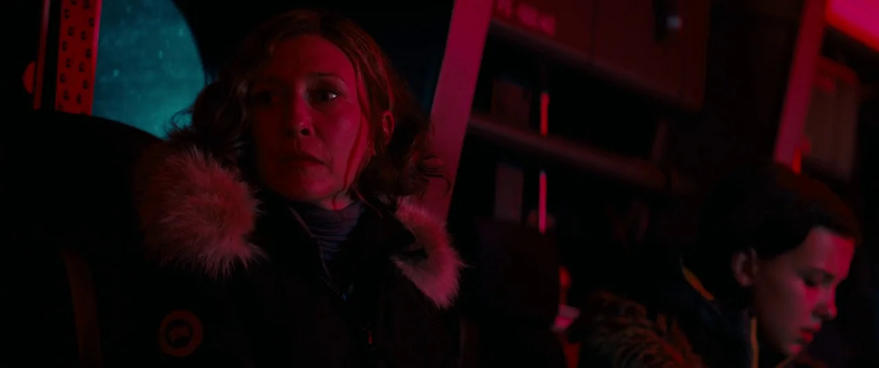 Godzilla: King of the Monsters (2019) movie still: medium — The interior of a darkened vehicle cabin is lit by intense red light. Two women sit next…