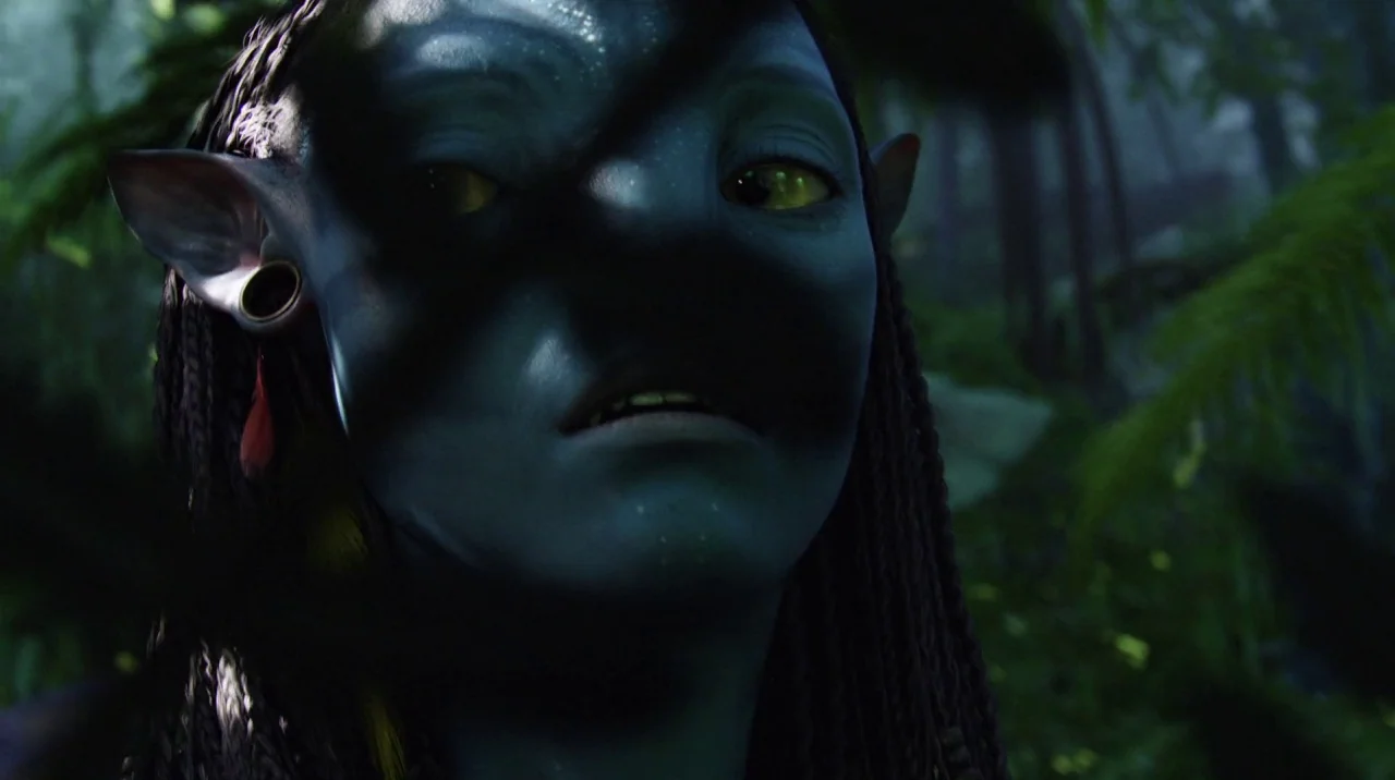 Avatar (2009) movie still: closeup — A dense, shadowed jungle environment with out-of-focus green ferns in the foreground and background. A…