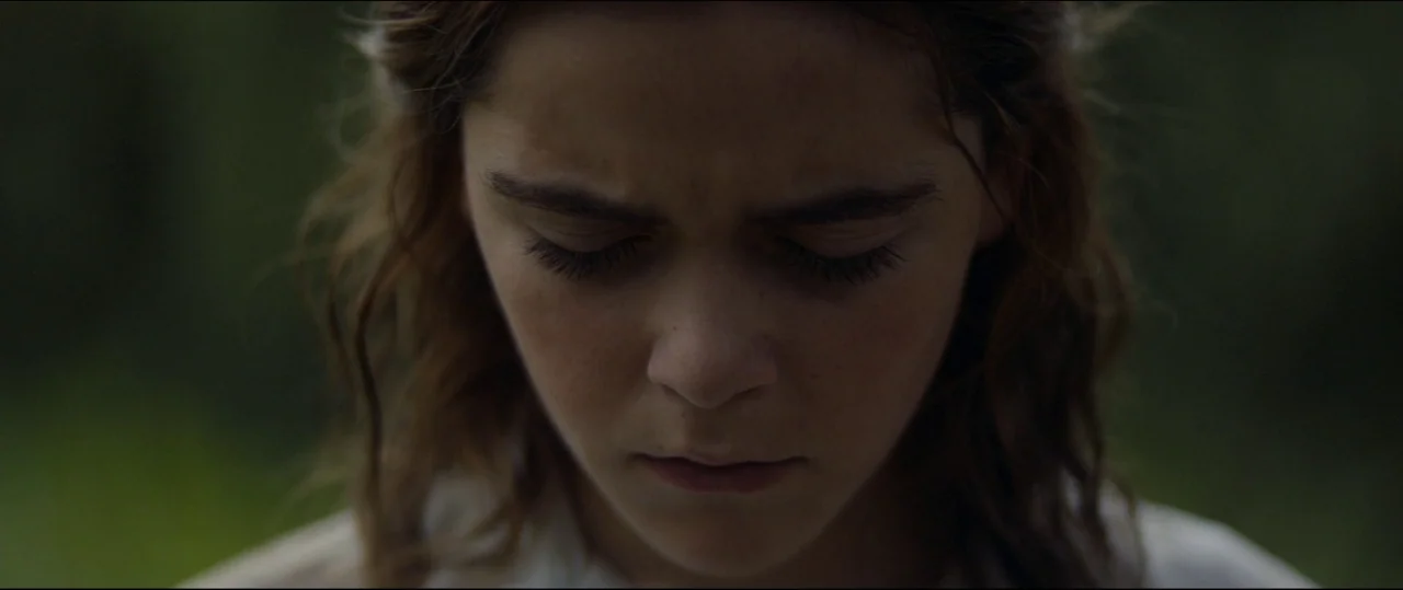 One & Two (2015) movie still: closeup — A dark outdoor space with indistinct foliage blurred in the out-of-focus background. A young woman with…