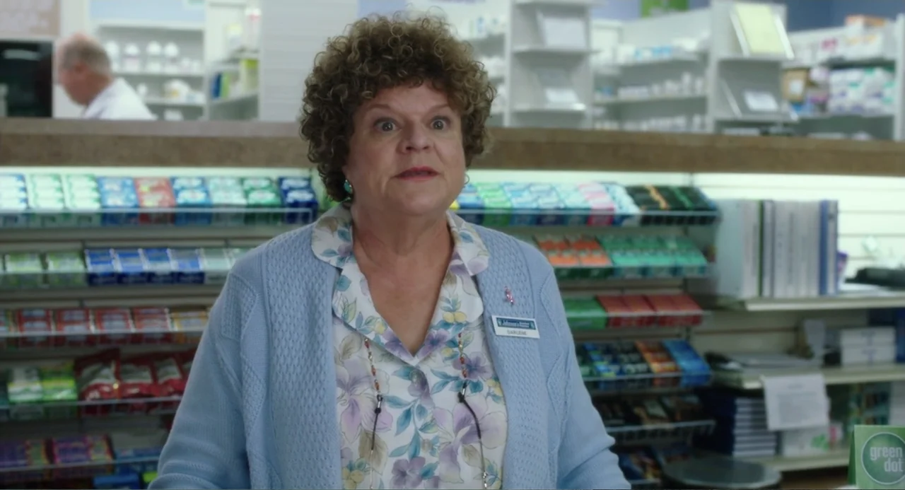 Blended (2014) movie still: medium — A well-lit pharmacy interior features shelves filled with various retail products and medication bottles. A…