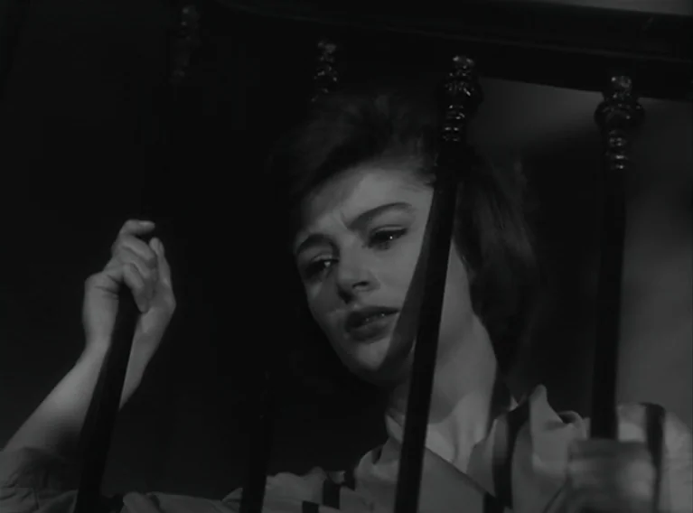 Head Against The Wall (1959) movie still: closeup — A dark interior staircase features vertical metal bars crossing the foreground of the frame. A…