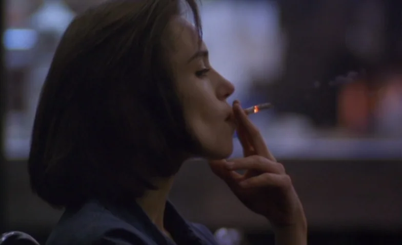 I Can’t Sleep (1994) movie still: closeup — A dark indoor space with blurred background lights suggesting a late-night setting. A woman is seen in…