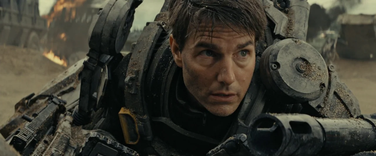 Edge of Tomorrow (2014) movie still: closeup — A war-torn field features scattered debris, smoldering wreckage, and smoke in the background. A…