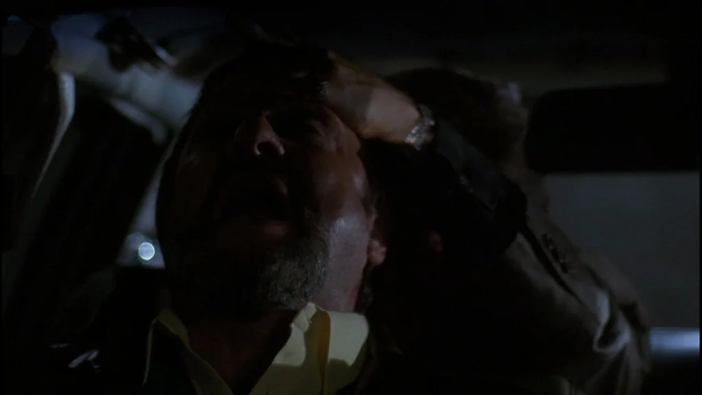 Goodfellas (1990) movie still: closeup — The interior of a dark car at night shows a man with an agonized expression. A hand is pressed firmly…