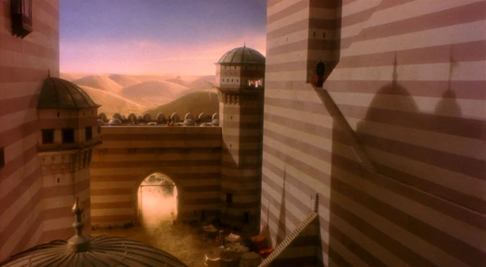 The Adventures Of Baron Munchausen (1988) movie still: establishing — A fortress with alternating beige and dark striped masonry overlooks a desert…