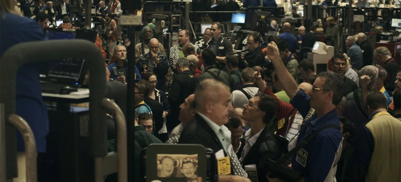 10 Billion: What's On Your Plate (2015) movie still: medium — A high-density financial market floor features rows of desks and screens under…