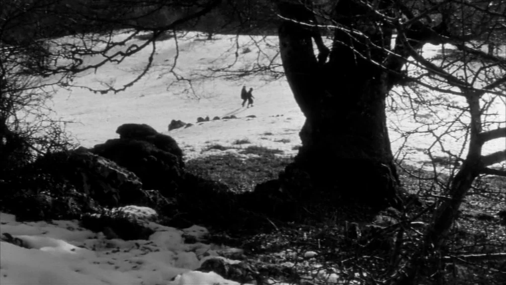 Falstaff (Chimes at Midnight) (1965) movie still: wide — A snowy hillside features large, leafless dark trees in the foreground. Two small figures…