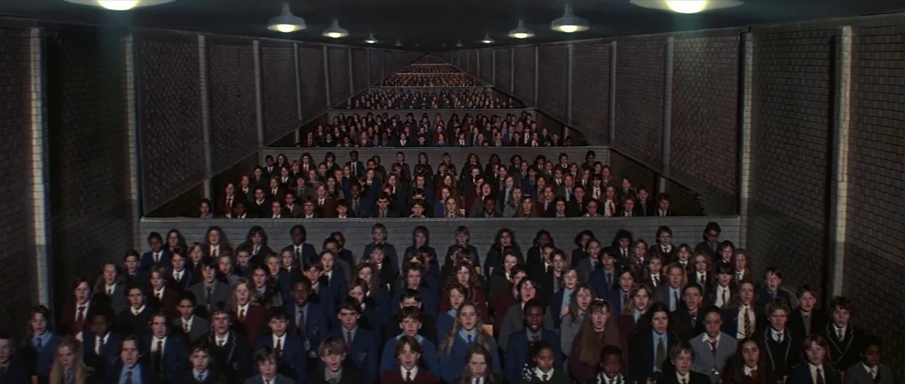 Pink Floyd The Wall (1982) movie still: wide — A massive, deep auditorium features tiered brick seating arrangements filled with many young…