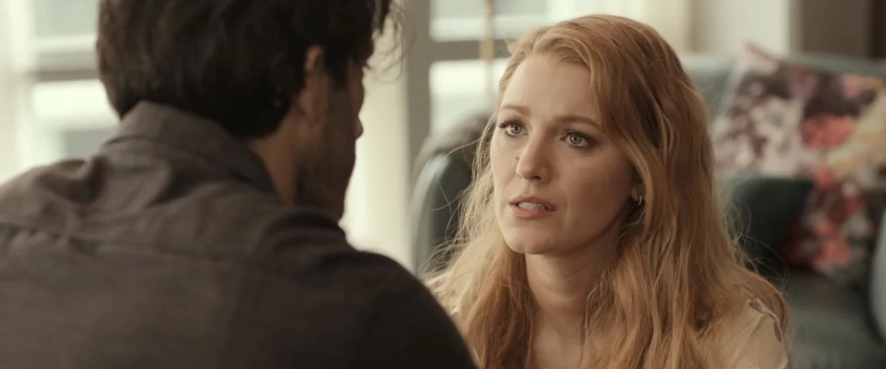It Ends with Us (2024) movie still: medium — A well-lit interior room with blurred out furniture in the background. A woman faces an out-of-focus…