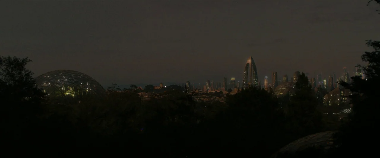 After Yang (2021) movie still: establishing — A nighttime panoramic view of a futuristic city skyline with several prominent glass domes. Dark…