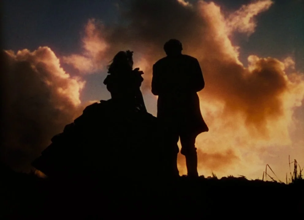 Gone with the Wind (1939) movie still: fullbody — A field at dusk with a large, dramatic orange-tinted cloud formation in the sky. A man and a woman…