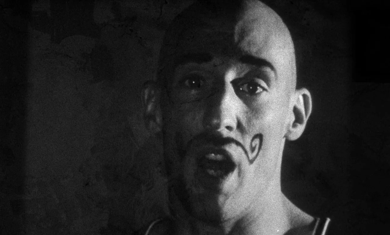 Go Down Death movie still: closeup — A dark space provides the setting for a high-contrast black and white portrait. A bald man faces the camera…