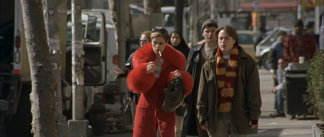 Igby Goes Down (2002) movie still: fullbody — A busy city sidewalk during the day features pedestrians walking in urban clothing. A woman in a red…